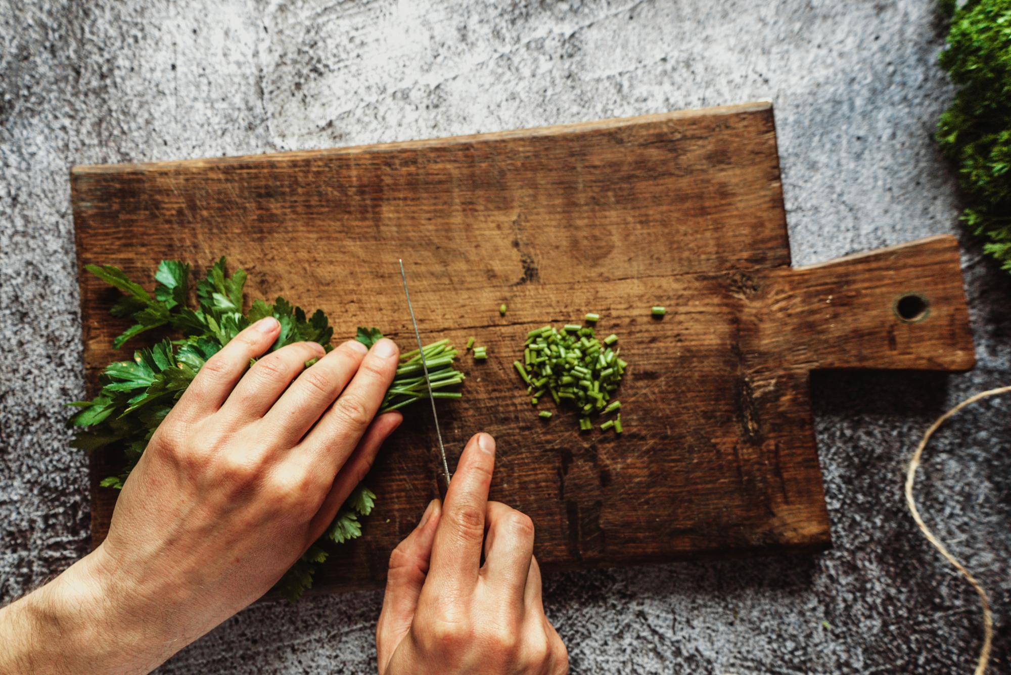 Chef hand arranging herbs on a wooden board